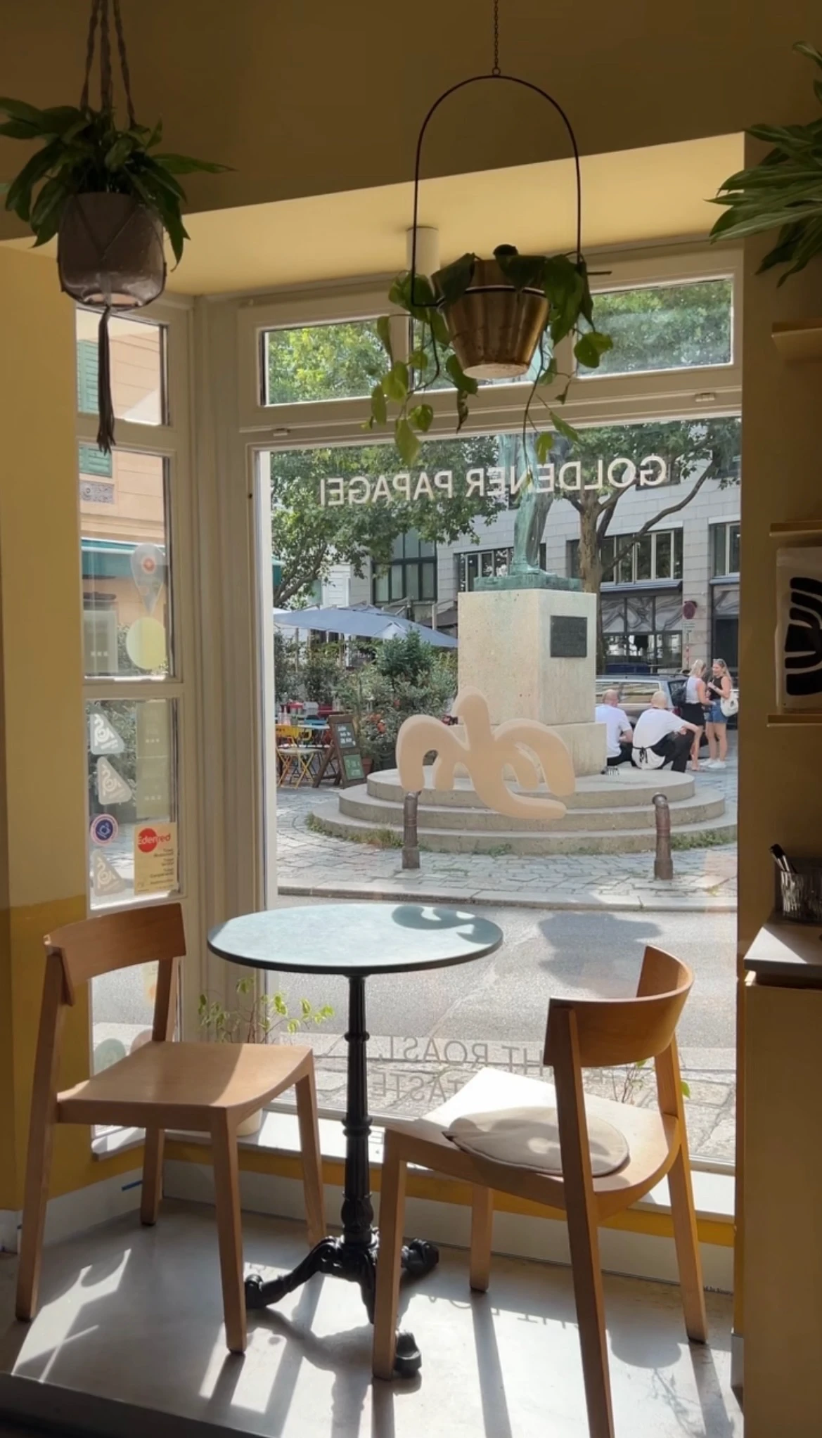 Gemütlicher Platz am Fenster in einem Café mit Blick auf eine Straße und ein Denkmal im Freien